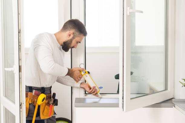 handsome young man installing bay window in a new house construction site
